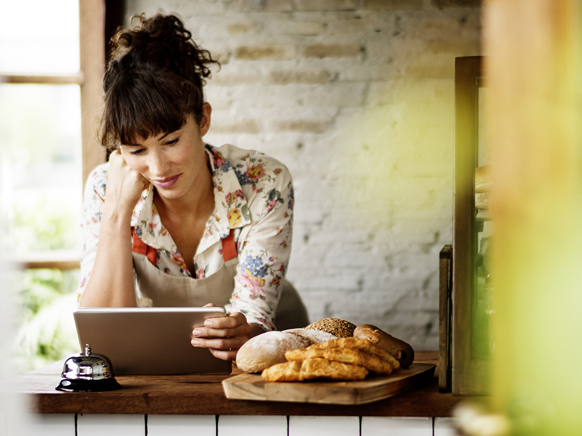 woman in bakery reading on tablet
