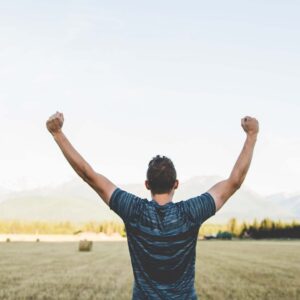man raising fists in triumph on farm