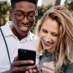 A man shows his phone to a smiling woman
