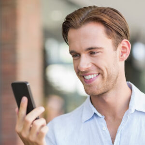 A smiling man looks at his phone