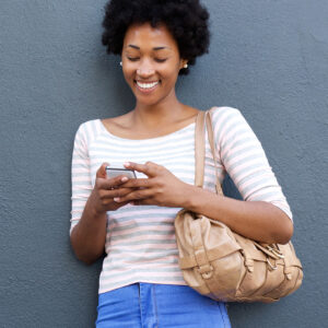 A young woman smiles and looks at her phone