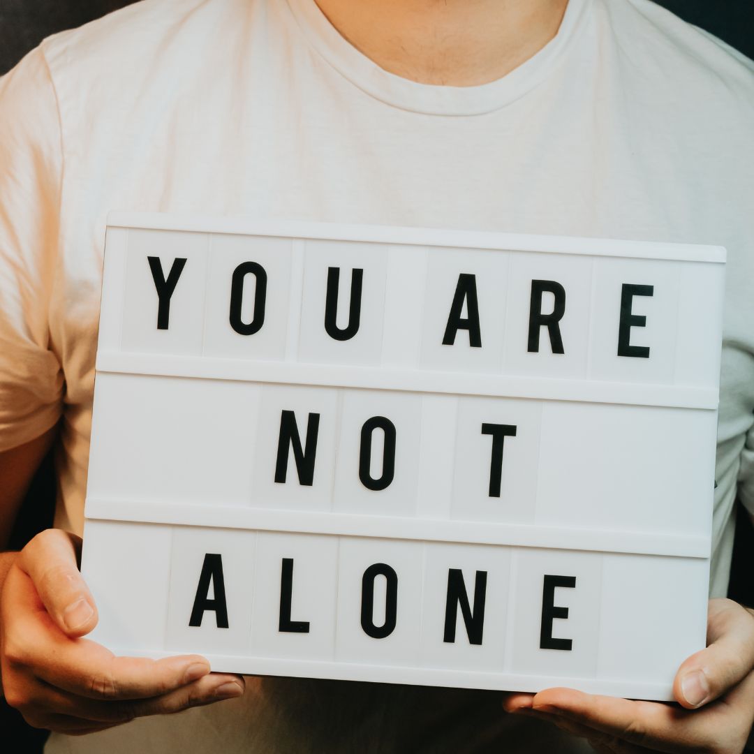 holding a sign that says you are not alone